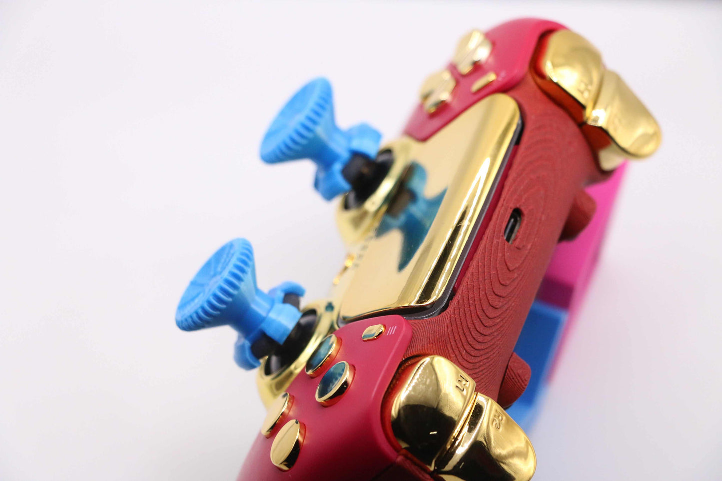 Blue PS4PS5Xbox thumbstick extenders attached to red and gold gaming controller