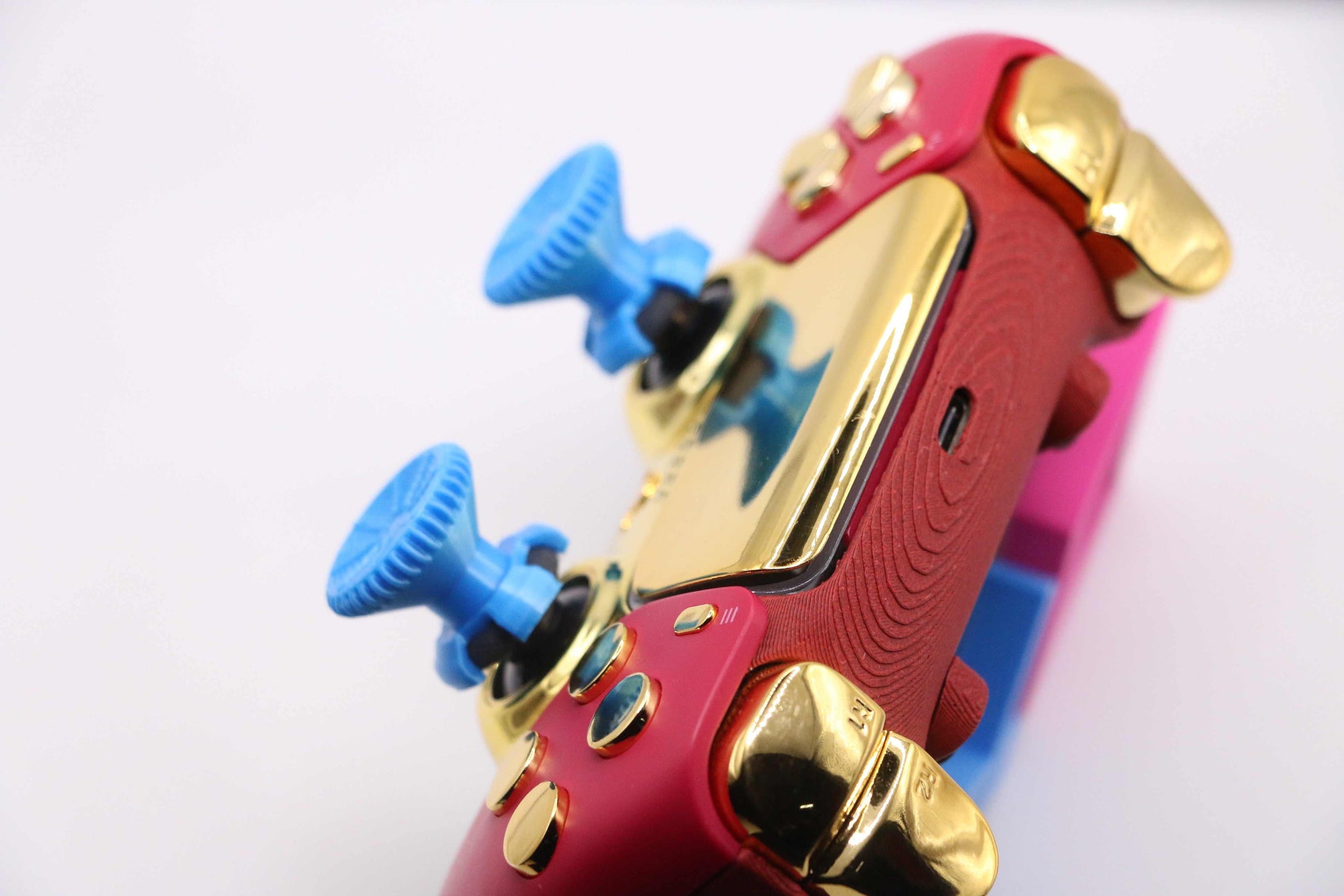 Blue PS4PS5Xbox thumbstick extenders attached to red and gold gaming controller