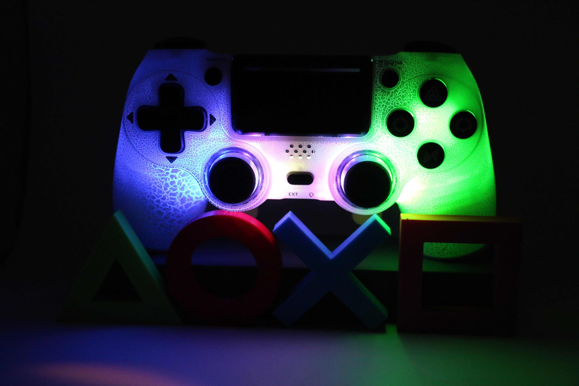 LED PS4 controller illuminated with colorful lights and PlayStation symbols in front