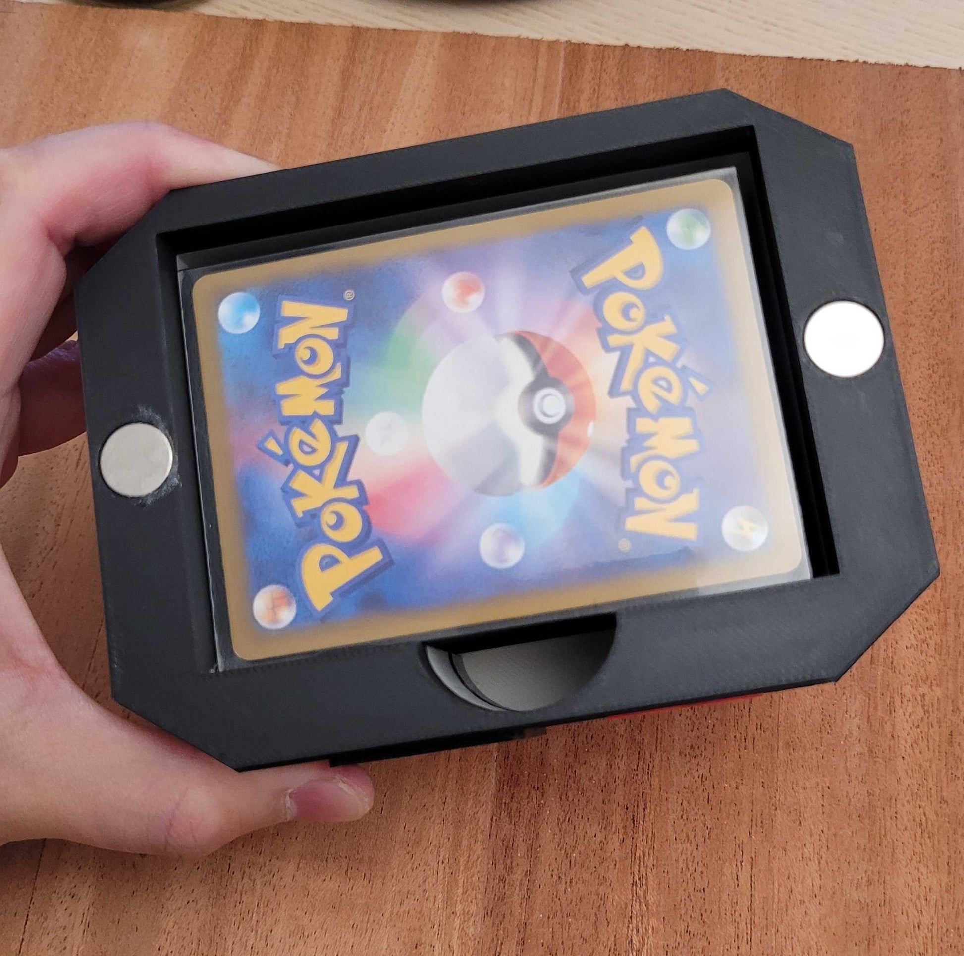 Hand holding black 3D printed Pokemon Center Deck box with magnetic roof securing a Pokemon card inside